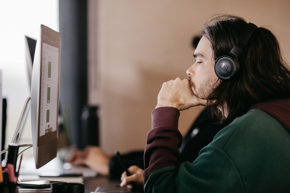 A music producer with headphones on looking thoughtful