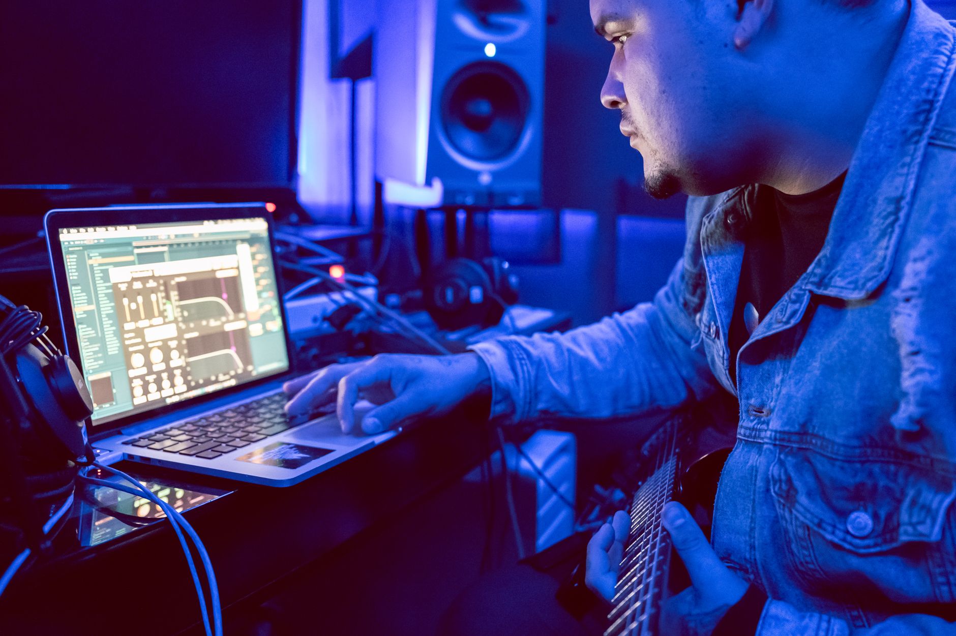 A young musician working on a laptop in a recording studio