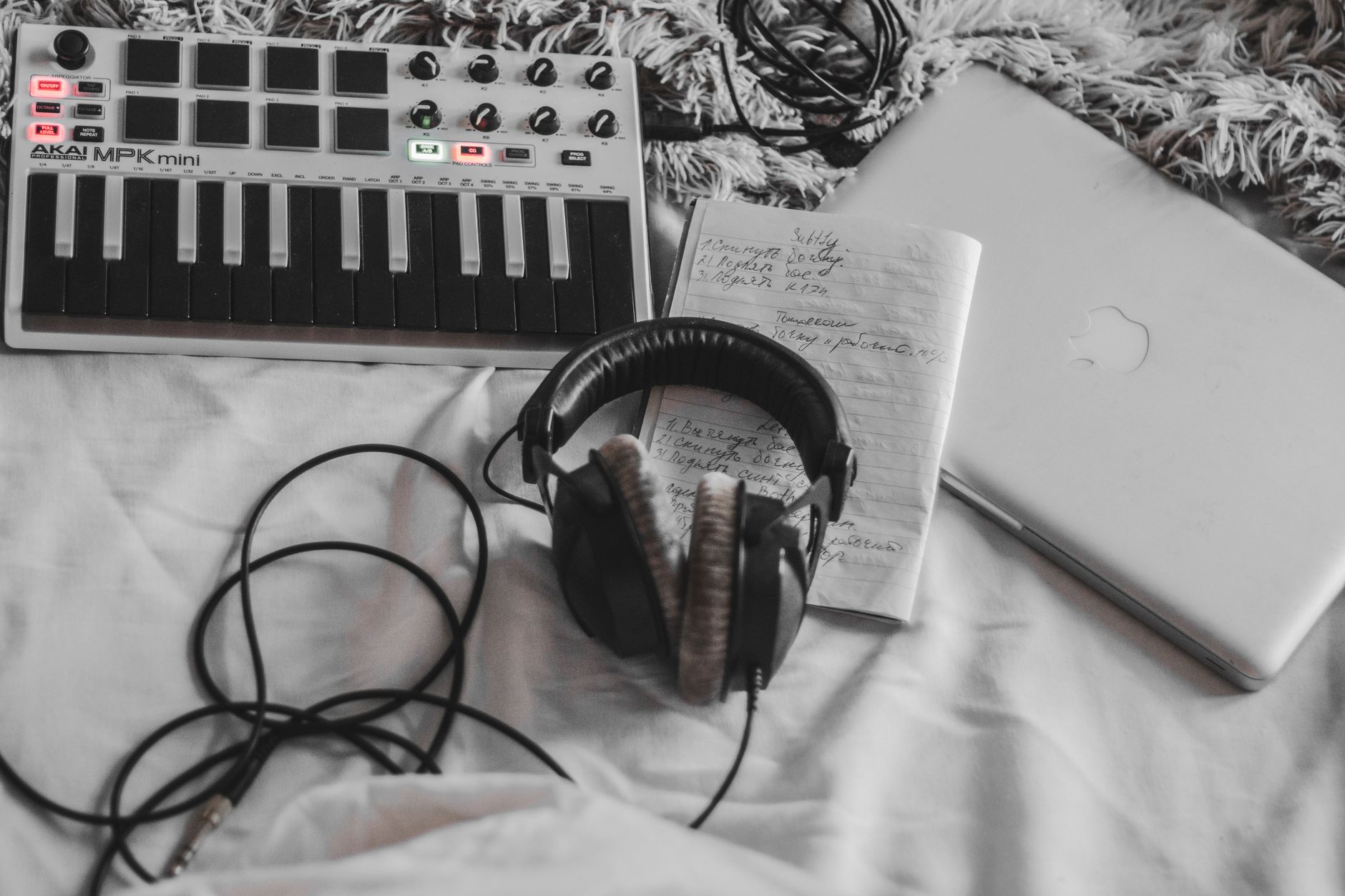 A quiet home music production setup with a MIDI controller, headphones, and laptop