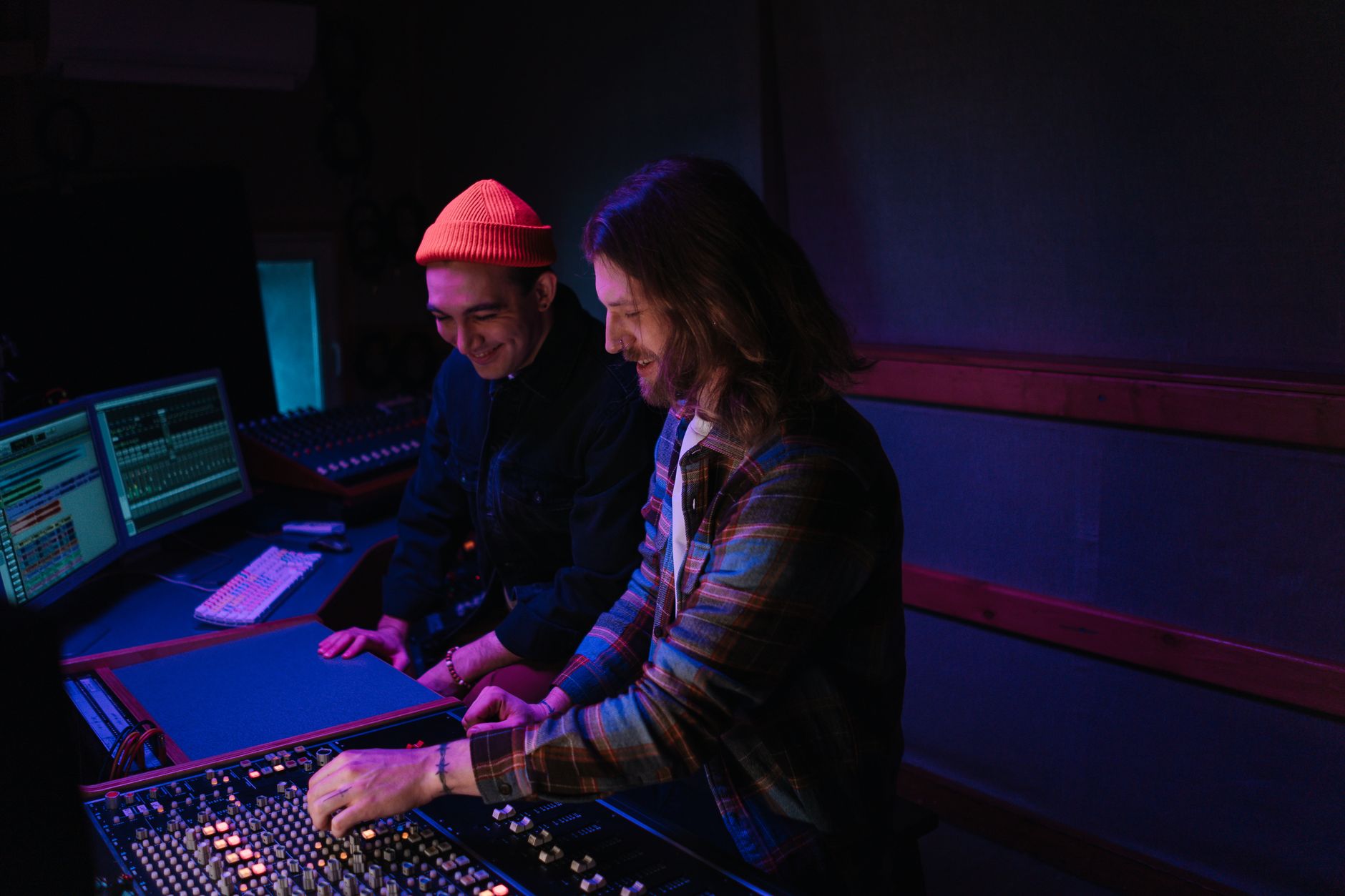 Two people working together at a mixing console in a studio