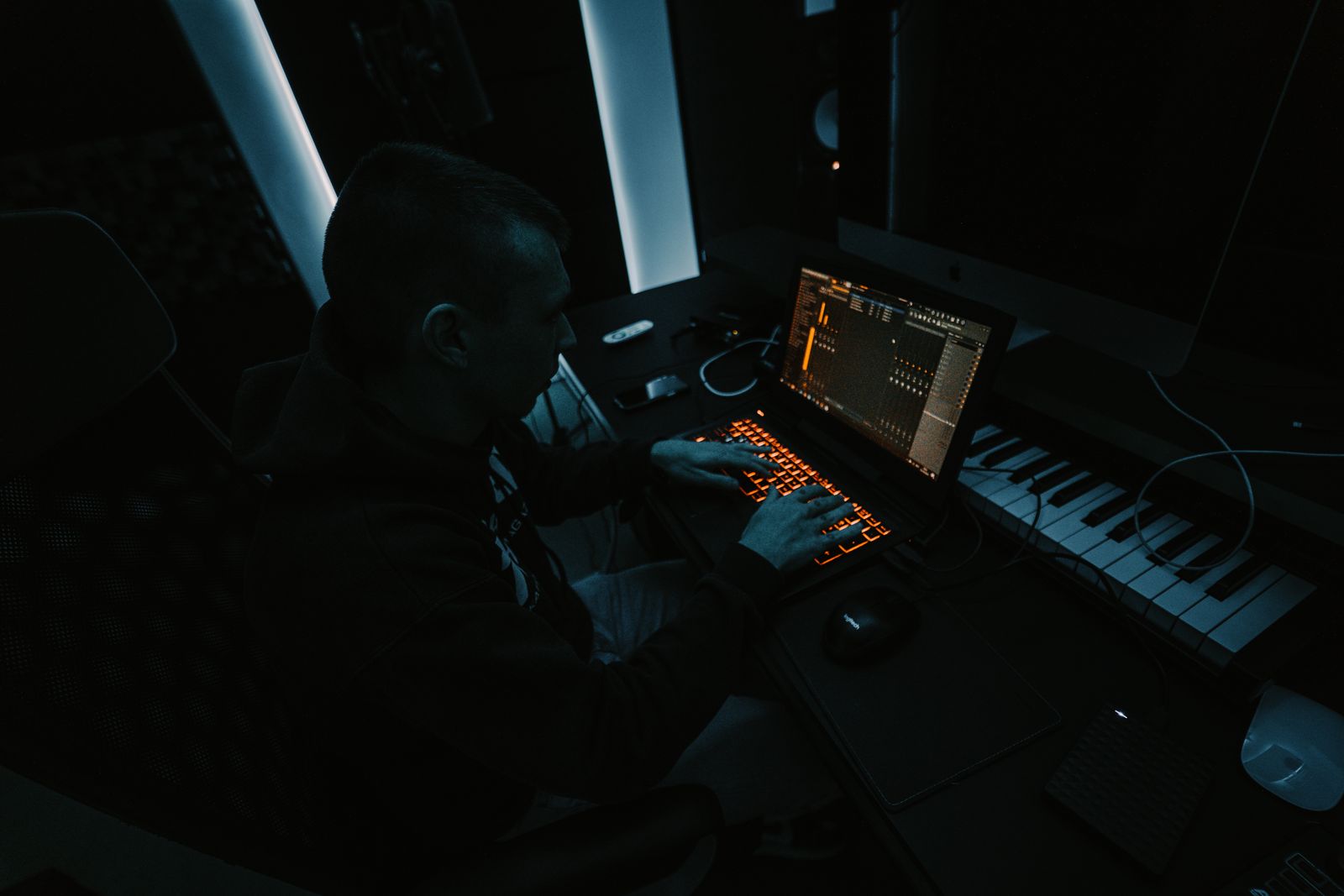 Music producer building a simple ad creative on a laptop in a dim home studio